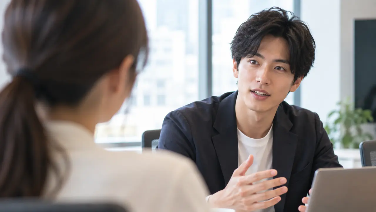 明るい会議室で、手前の女性の肩越しに話している男性を映した写真